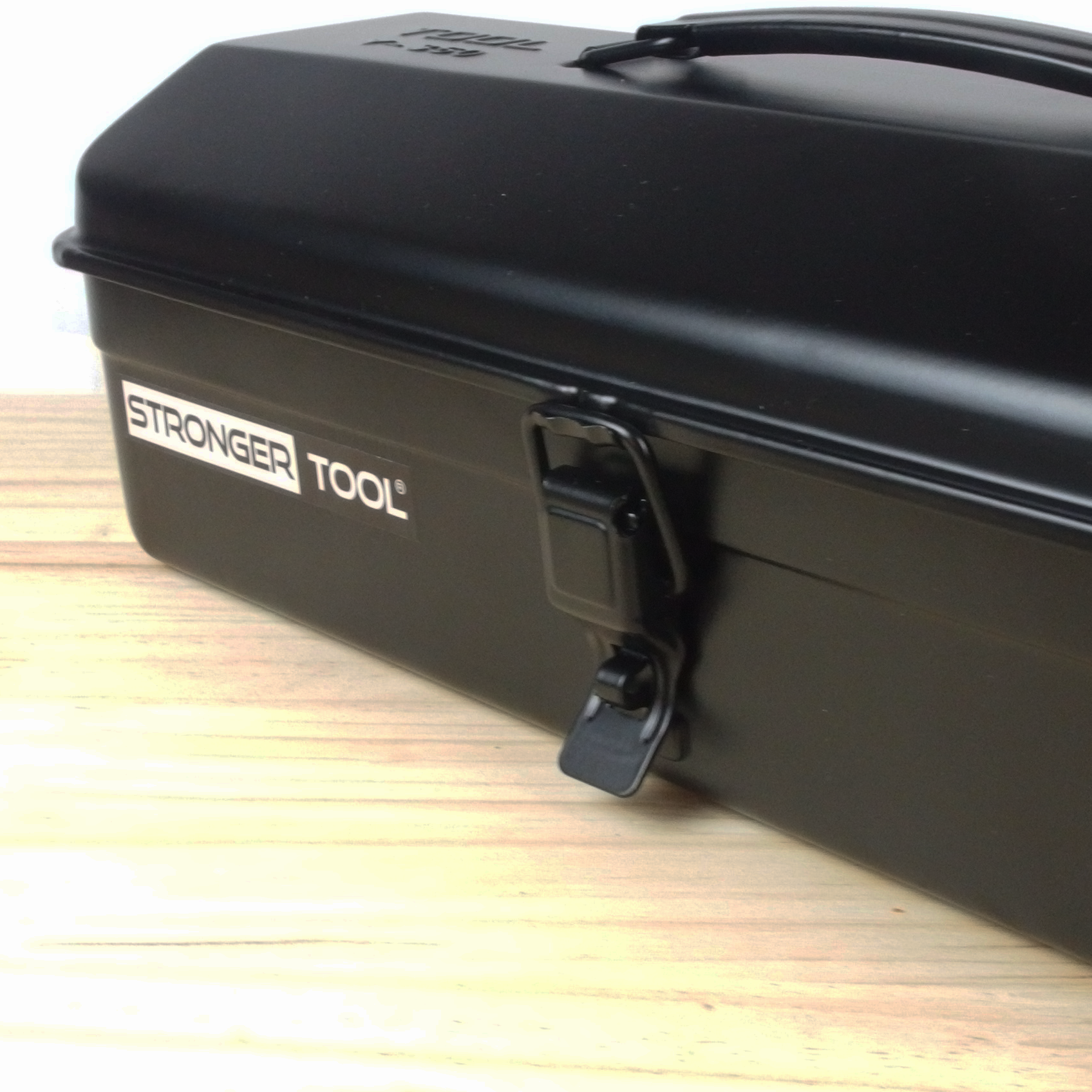 Black tool box with 'Stronger Tool' branding on a wooden surface